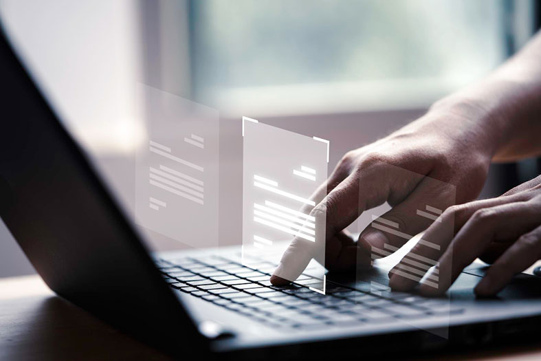 Montagem digital de uma pessoa usando um laptop enquanto pequenas telas se projetam acima do teclado.