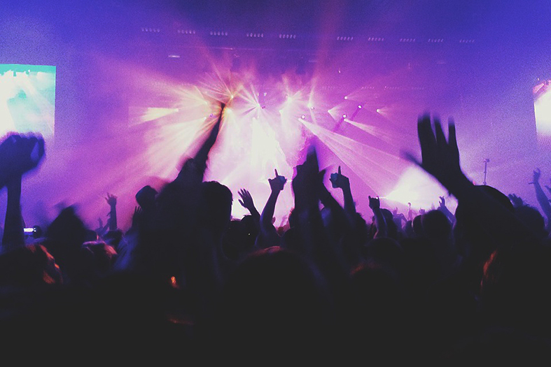 pessoas em uma festa com as mãos levantadas na frente do palco