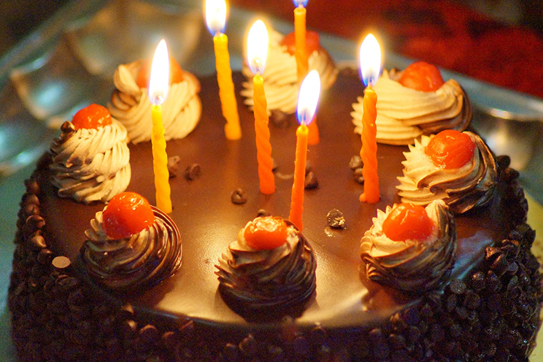 Bolo decorado com velas de aniversário acesas.