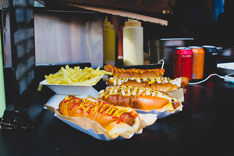 Três cachorros-quentes e uma porção de batatas fritas em um balcão de lanchonete.