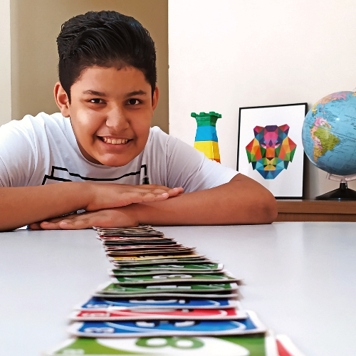 menino se debruça sobre mesa cheia de cartas de baralho