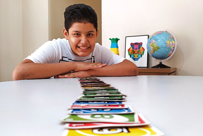 menino se debruça sobre mesa cheia de cartas de baralho