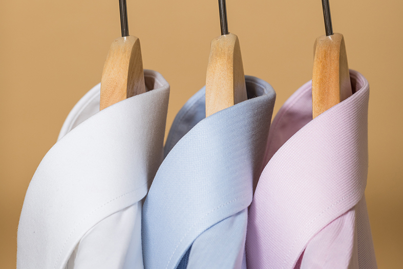 Camisas brancas e lilás penduradas em cabides.