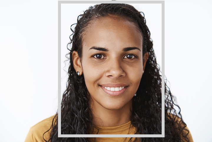 Mulher negra de cabelos anelados sorri para a câmera.
