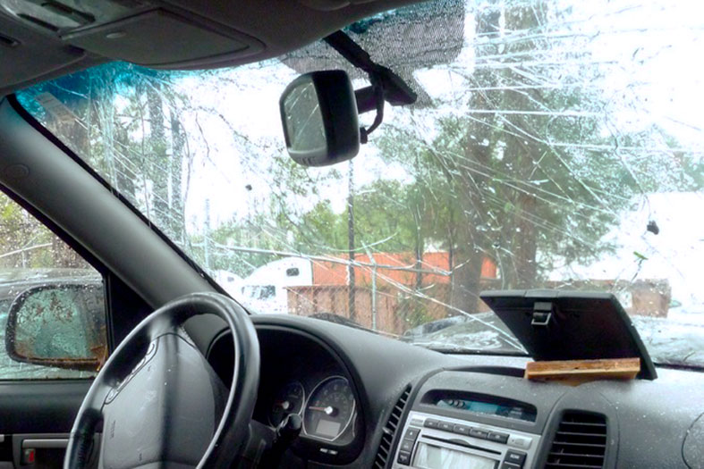 Interior de um carro com foco no para-brisa rachado.