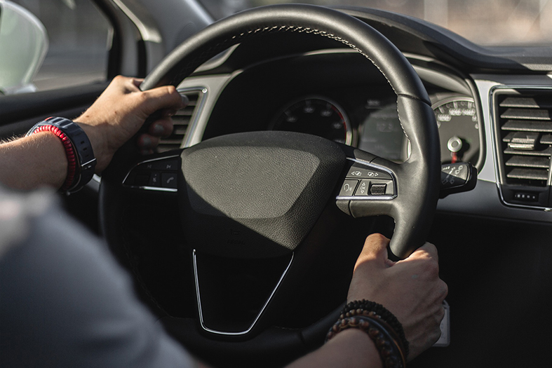 Homem segura volante de automóvel com as duas mãos.