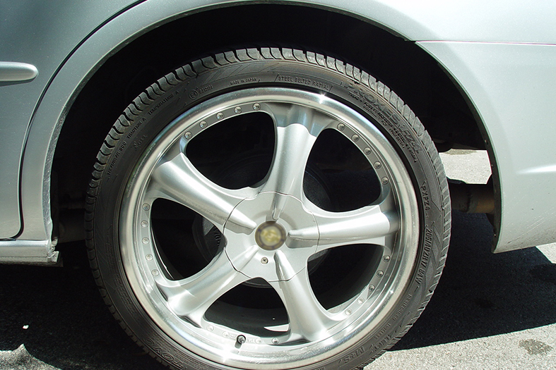 lateral traseira e roda de um carro na cor prata.