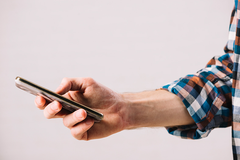 Mão de um homem segura um celular do tipo smartphone.