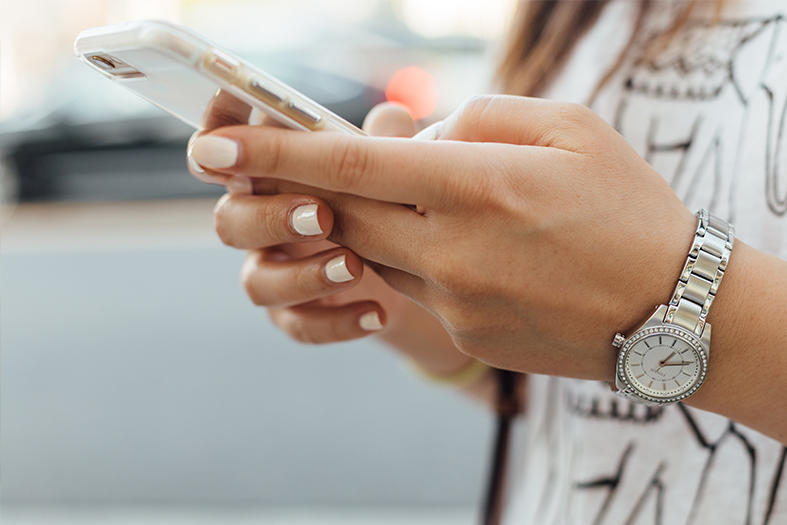 Detalhe de mãos de mulher usando um smartphone.