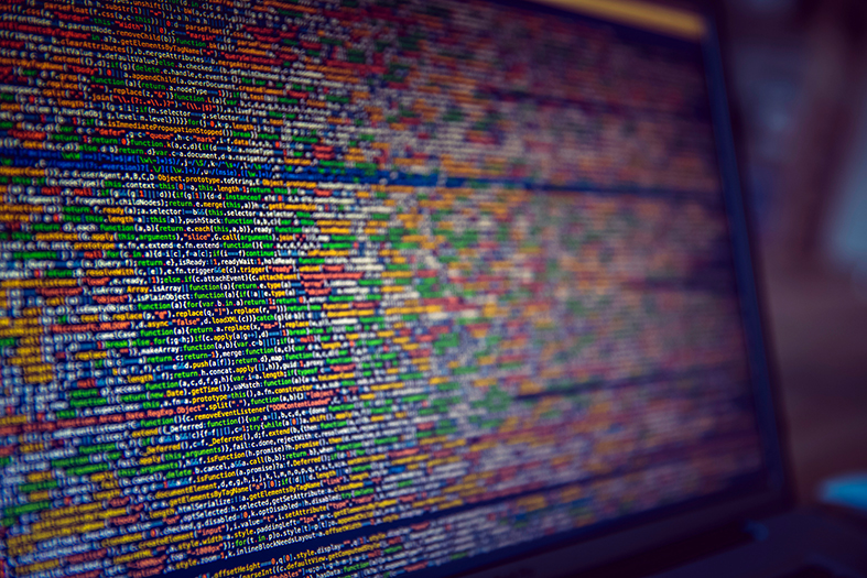 Detalhe de tela de computador repleta de linhas de código de informática.