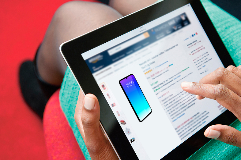 Mulher realiza compra de celulares online através de tablet repousado em seu colo.