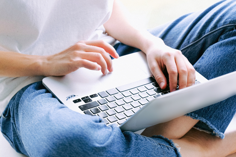 mulher usando laptop apoiado nas pernas cruzadas