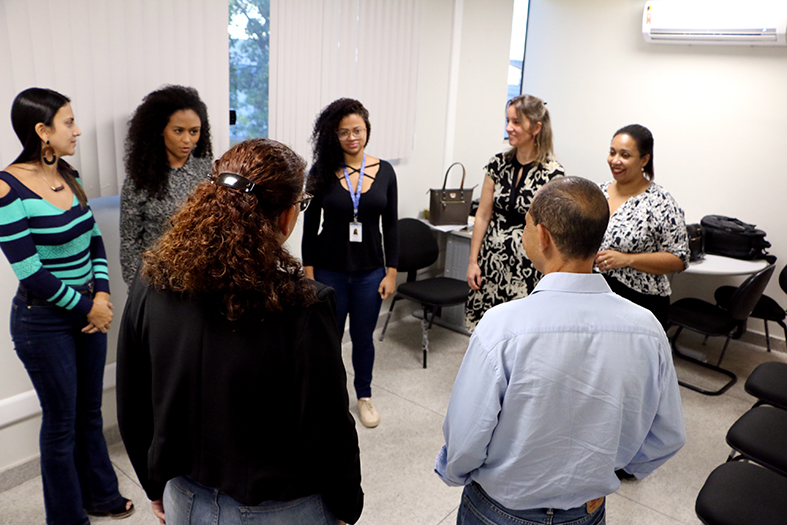 Grupo de 6 mulheres e um homem de pé em círculo.