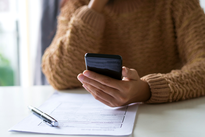 Mulher conferindo a fatura de seu telefone celular.