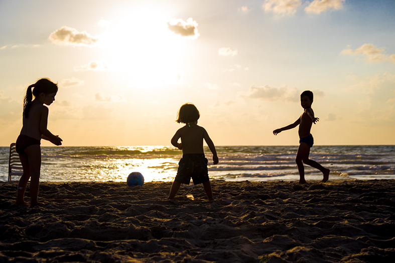 silhueta de três crianças brincando na praia