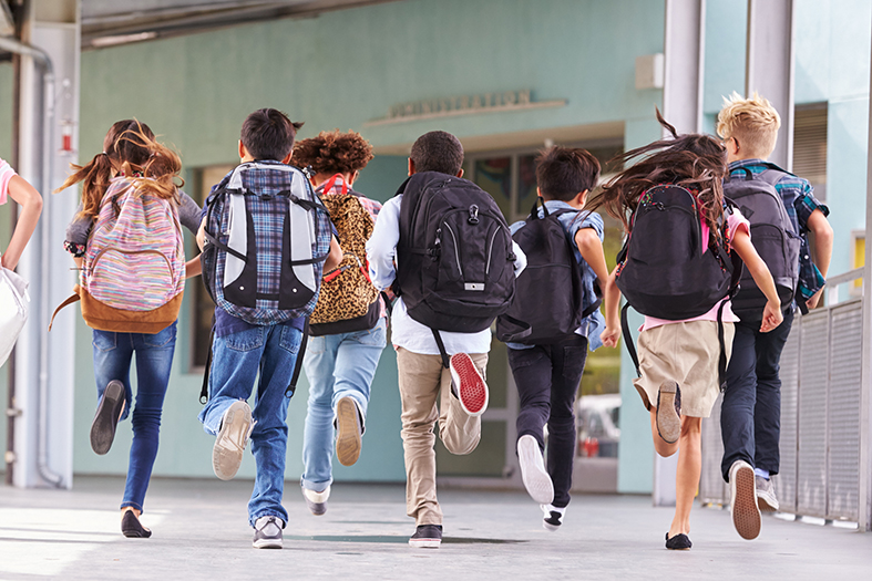 Grupo de estudantes correndo para entrar na escola