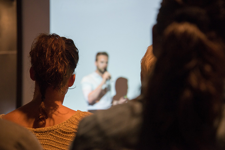 Pessoas assistem a um professor dando aula.