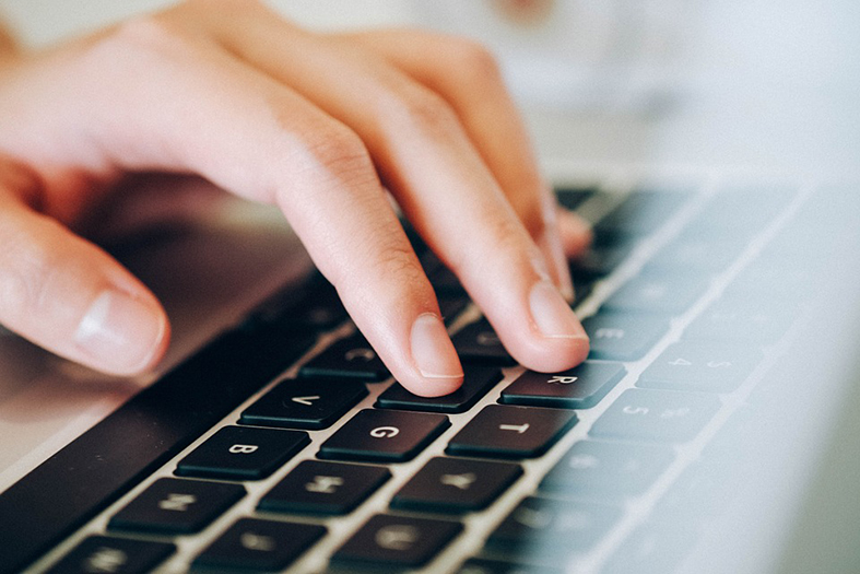 mão de um homem adulto digitando em teclado com teclas na cor preta.