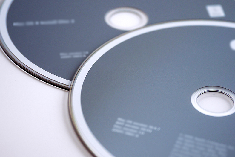 Detalhe de dois discos do tipo DVD com rótulo na cor cinza.