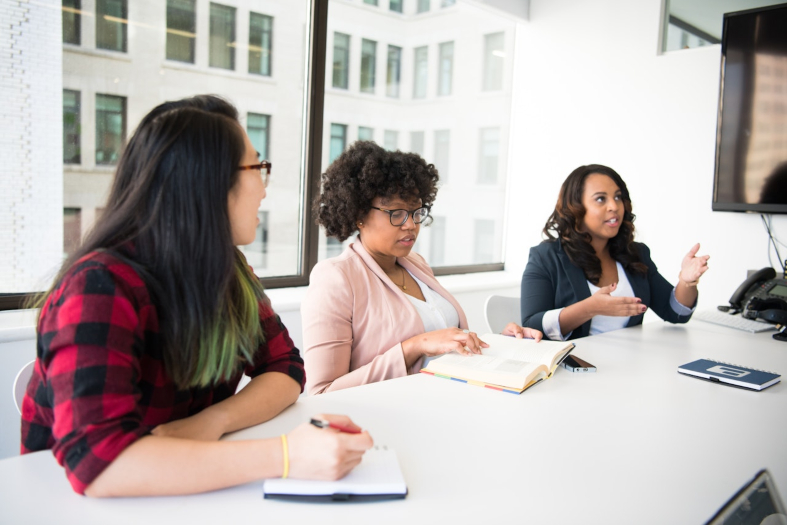 Três mulheres em uma reunião.