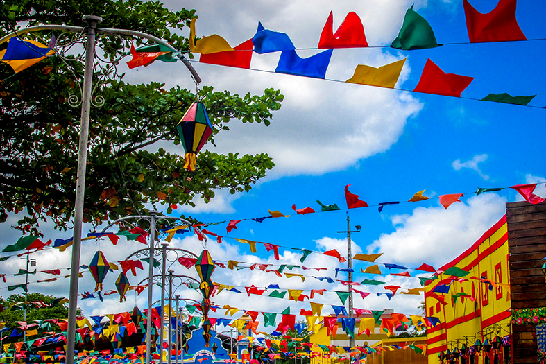 Praça adornada por bandeirolas temática de festa junina.