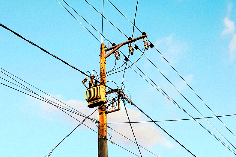 Poste com fiação elétrica e transformador.