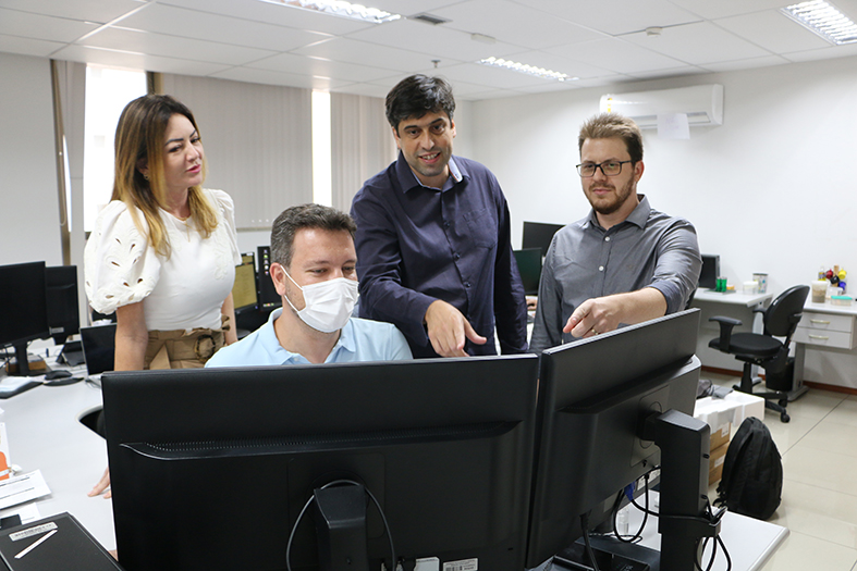 Equipe de servidores em frente a um computador na secretaria de tecnologia da informação do tjes.