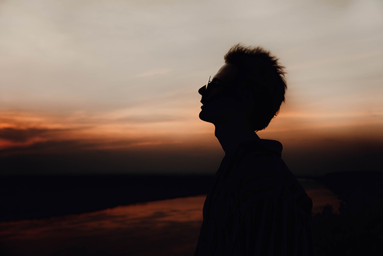 Silhueta de homem em contraste com por do sol.