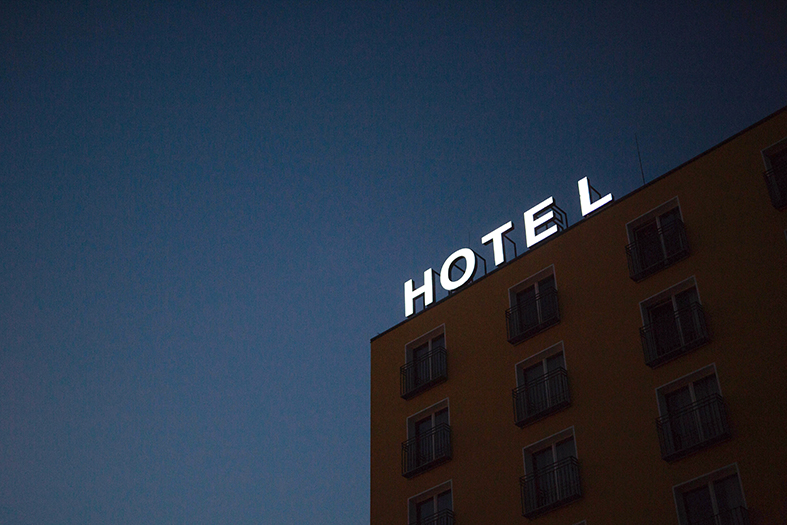 Fachada de um hotel onde se vê um letreiro luminoso escrito a palavra hotel