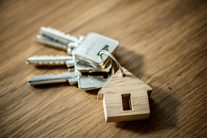 Molho de chaves com um chaveiro em formato de casa sobre uma mesa de madeira.