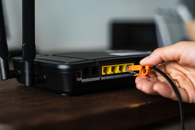 mão conecta um cabo ethernet/cabo de internet em um modem.