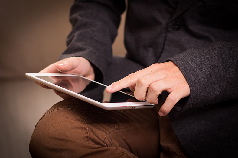 Homem sentado digitando em um tablet