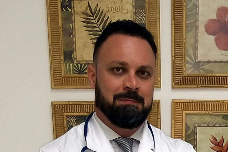 Médico urologista Camilo Milanez, homem de pele parda, cabelos e barba de cor preta.