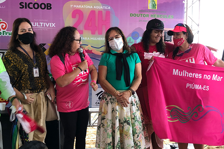 Grupo de mulheres posa para fotografia em local de premiação de evento esportivo.
