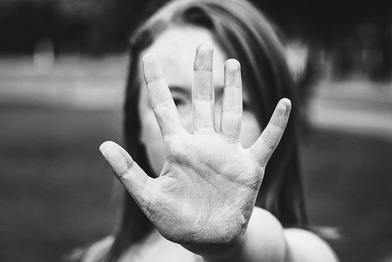mulher com a mãe estendida como se fosse impedir algum movimento