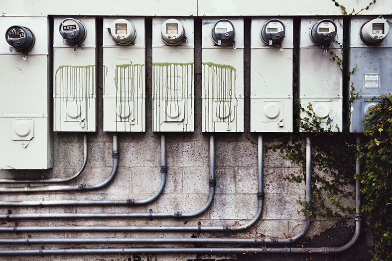 oito medidores de energia elétrica lado-a-lado em uma parede externa.