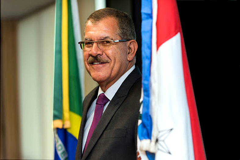 Ministro Humberto Martins sorri para a câmera. Ele tem a pele parda, cabelos e bigode pretos e usa óculos.