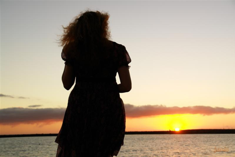 silhueta de mulher vendo um pôr do sol.