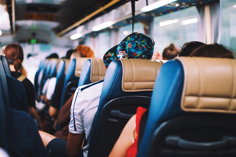 Visão das costas de poltronas de ônibus de turismo cheio de passageiros.