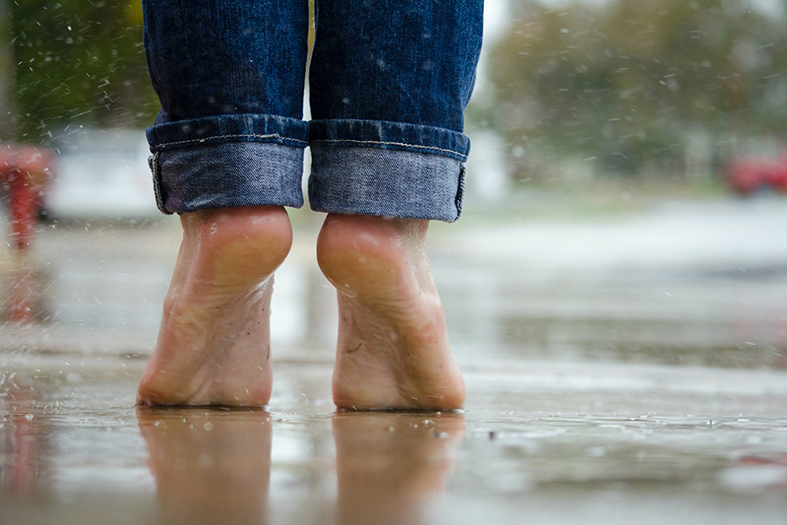 Pessoa em jeans azul e pés descalços.