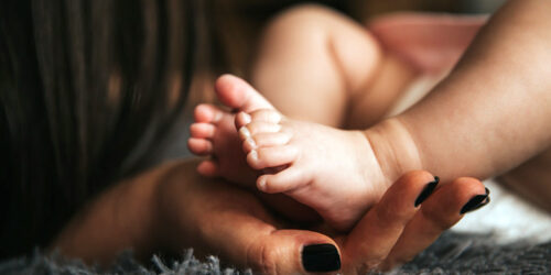 fotografia de pessoa segurando os pés do bebe