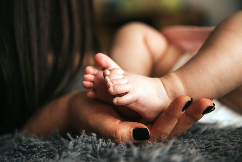 fotografia de pessoa segurando os pés do bebe