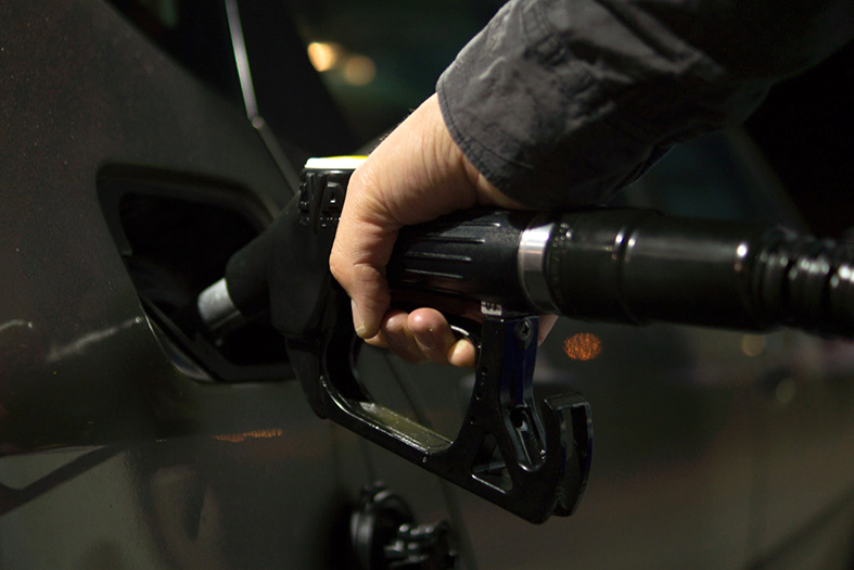 Detalhe de mão segurando injetor de combustível abastecendo um carro.