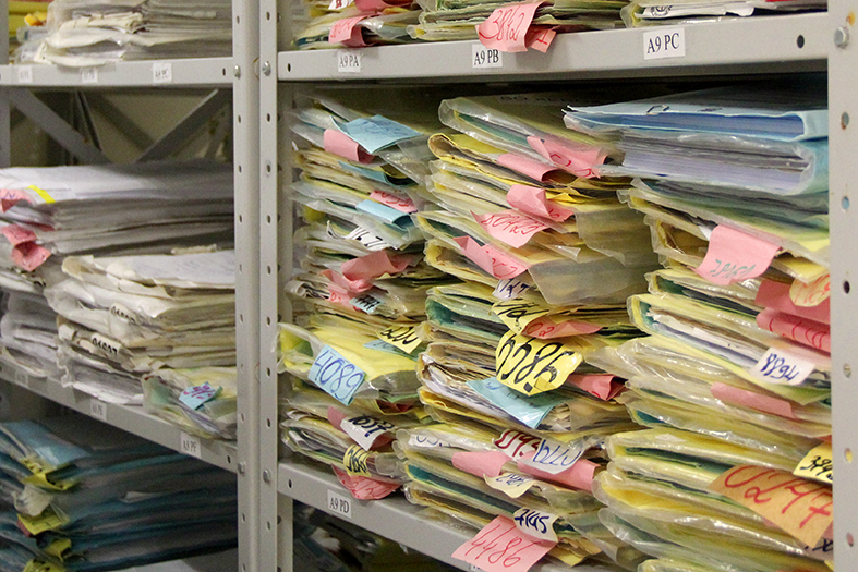 Pilhas de processos estocados em estantes de aço.