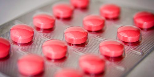embalagem de medicamento repletos de drágeas na cor vermelha.