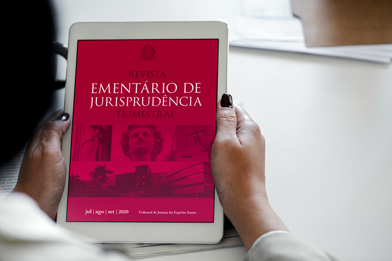 mão de uma pessoa negra segurando um tablet. na tela a capa da terceira edição da revista ementário do ano de 2020.