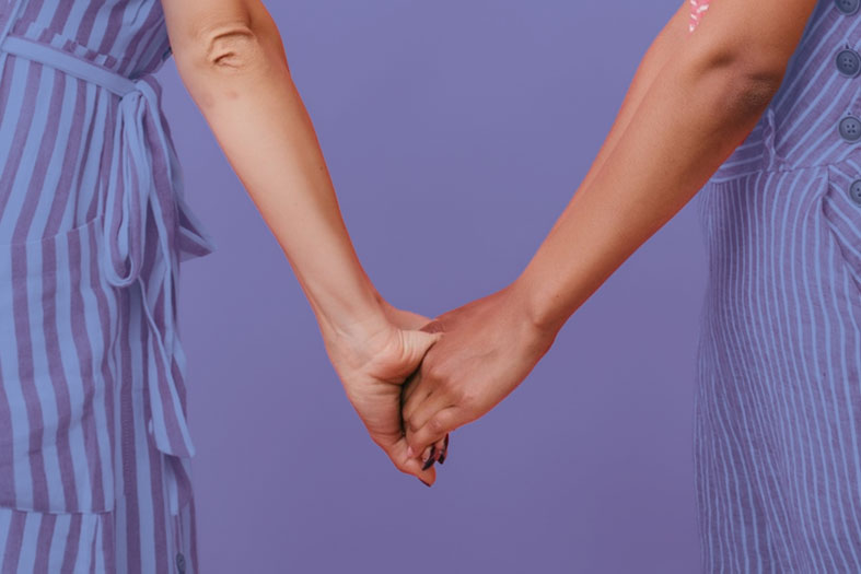 Duas mulheres dando as mãos.