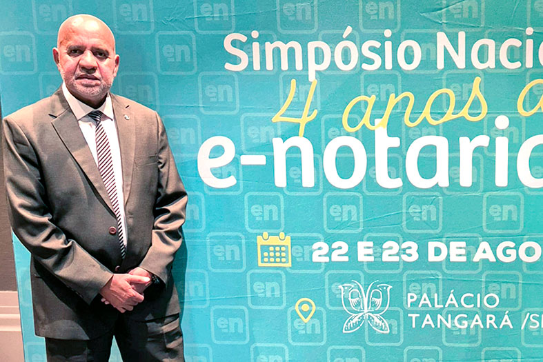 O Corregedor-geral da Justiça, desembargador Willian Silva, posa para foto em frente ao painel do Simpósio Nacional que celebrou 4 anos de e-notariado.