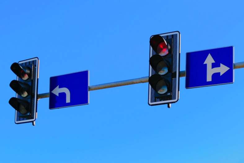 Semáforos com luz vermelha acesa e placas direcionais.