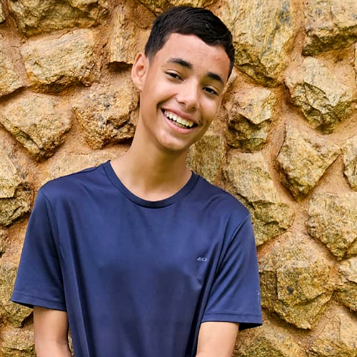 O adolescente Paulo Victor tem 15 anos, a pele na cor branca, o cabelo preto e ele veste uma camisa na cor azul marinho.